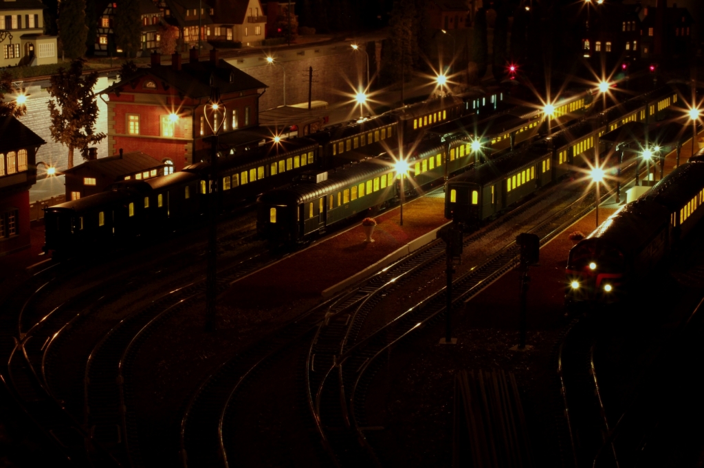 Vue du réseau de trains électriques miniatures avec locomotive éclairée à l'arrêt.